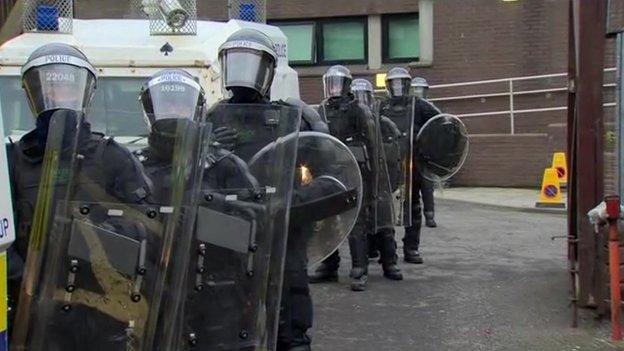 Police officers in riot gear alongside vans waiting to leave Antrim PSNI base