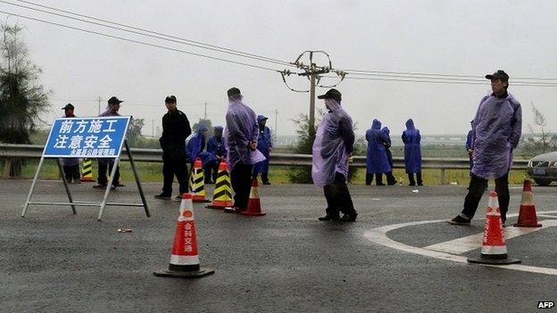 Officials check vehicles on the road to Oubei outside Weizhou as demolition work goes on (30 April)