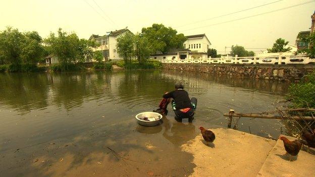 A woman washing clothes in the pond in Zhou Yongkang's home village of Xiqiantou, in Jiangsu province