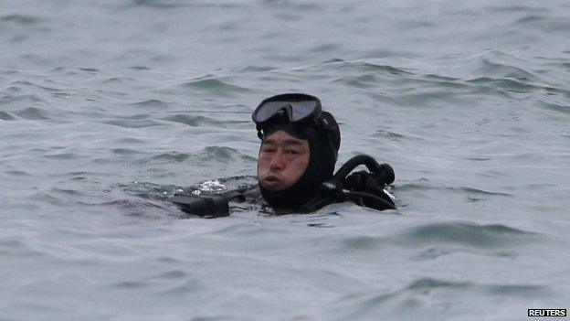 A South Korean diver rests in the water during the rescue operation of the capsized passenger ship "Sewol", in the sea off Jindo April 18, 2014. A junior officer was steering the South Korean ferry when it capsized two days ago, investigators said on Friday, as rescuers battled strong tides and murky waters to search for hundreds of missing, many of them school children, feared trapped in the vessel