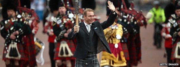 Glasgow 2014 ambassador Sir Chris Hoy leads the Scots Guards 1st Battalion Pipes and Drums up The Mall as he carries the empty baton towards Buckingham Palace.