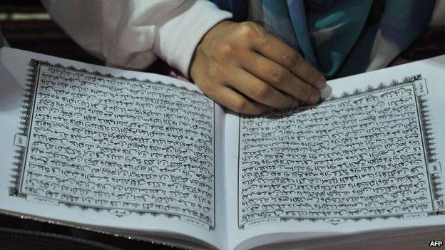 File photo: A woman reads a copy of the Koran