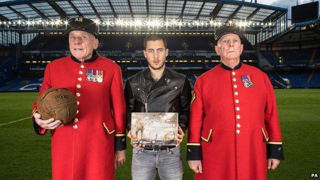 Chelsea and Belgium footballer Eden Hazard with Chelsea pensioners Steve Lovelock (left) - holding a football - and Dave Thomson (right) at Stamford Bridge football ground, London