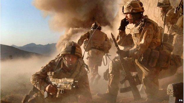 Soldiers in uniform in Afghanistan. Smoke is rising in the background