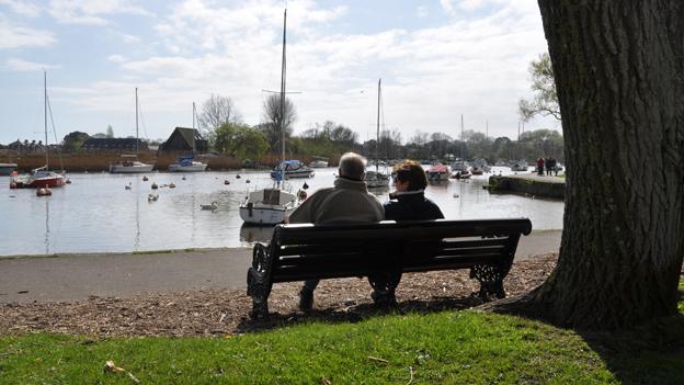 Couple sitting no bench looking at boats