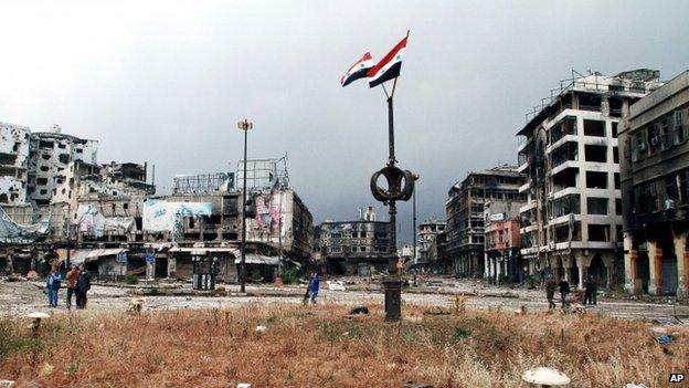 Syrian flags fly from a pole in the Old City of Homs (8 May 2014)