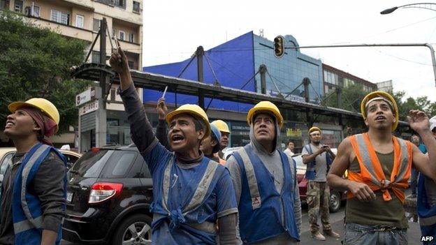 Workers look on after a strong earthquake in Mexico City on 8 May 2014.