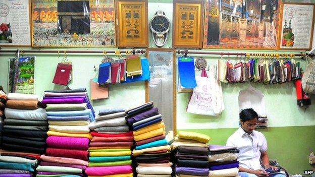 A shopkeeper sits amongst saris in Varanasi