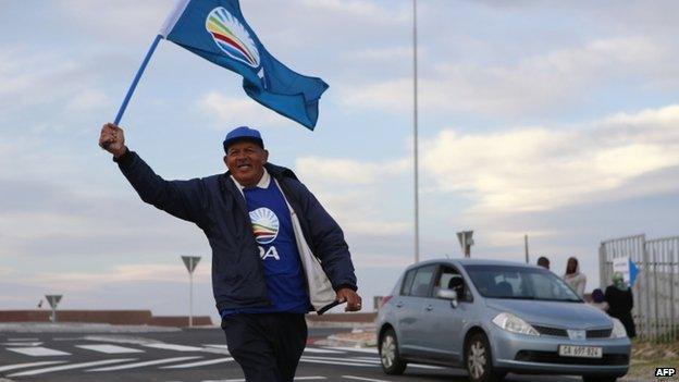 A Democratic Alliance supporter waves the party's flag outside the Colorado polling station in Mitchells Plain on the Cape Flats, South Africa, 7 May 2014