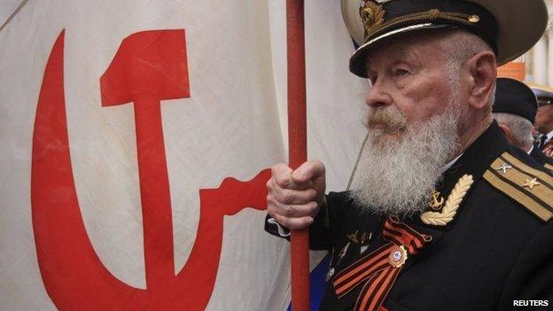 A former Soviet serviceman marches with a Soviet navy flag to mark Victory Day in the Crimean port of Sevastopol May 9