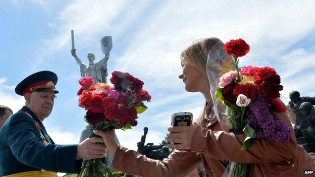 A woman gives flowers to a WWII veteran during a ceremony marking the Victory Day in the Ukrainian capital of Kiev on May 9,