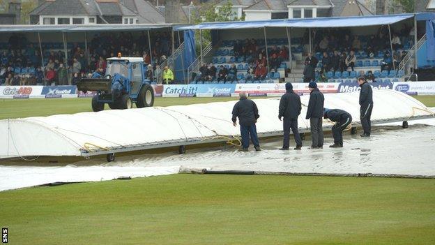 Groundsmen work to protect the pitch at Mannofield