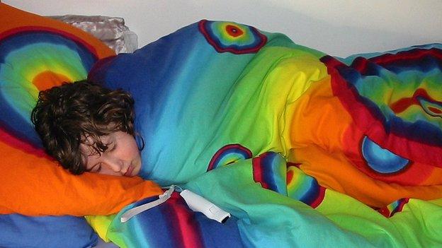 A boy sleeping in colourful bedsheets