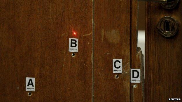 The red light from a laser lines up bullet holes on the bathroom door during the trial of Oscar Pistorius in Pretoria (12 May 2014)