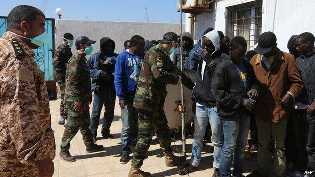 African migrants wait at a Libyan Naval forces post in Tripoli after their boat was intercepted en route to Europe and brought back to Libya, 10 April 2014