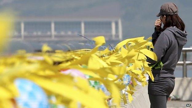 A volunteer wipes away tears near yellow ribbons with messages for the victims and missing passengers of the sunken ferry Sewol at a port in Jindo, south of Seoul, South Korea, 12 May 2014