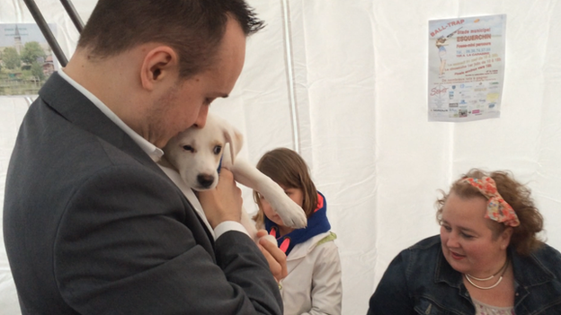 Christopher Szczurek of the National Front kisses a dog at community event