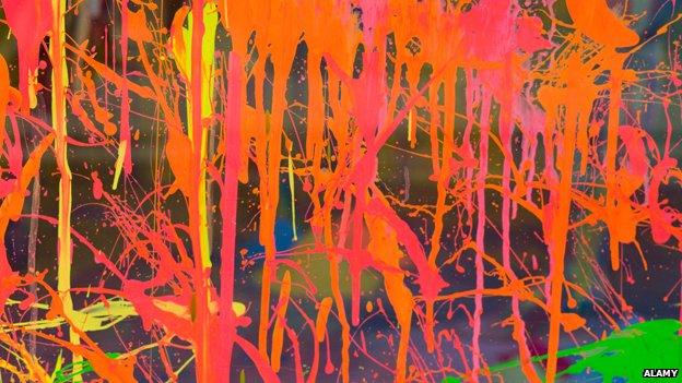 A glass window is splattered with orange and pink paint