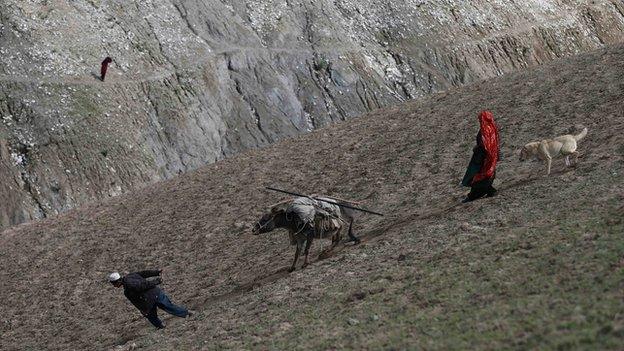 Villagers carry aid supplies on a donkey near the site of the Argo landslide