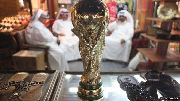 Arab men at a shoemaker's stall in a market in Doha, Qatar, with a replica of the FIFA World Cup trophy - 24 October 2011