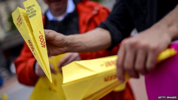 Supporters hold paper planes during a demonstration supporting a minimum wage of 4000 Swiss francs on May 7, 2014 in Geneva