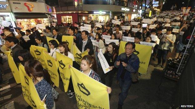 People march on a street after attending a candlelight vigil to commemorate victims of the sunken Sewol passenger ferry, and to denounce the South Korea government's handling of the disaster, in central Seoul on 10 May 10.