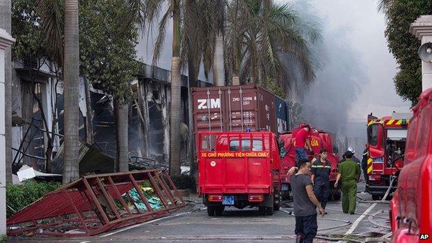 Firefighters stand across from the main entrance of Tan Than Industries as the Taiwanese bicycle factory burns, in Di An Town, Binh Duong province, Vietnam, Wednesday, May 14, 2014. Mobs burned and looted scores of foreign-owned factories in Vietnam following a large protest by workers against China"s recent placement of an oil rig in disputed Southeast Asian waters, officials said Wednesday