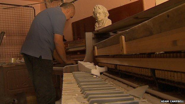 Amjad Manour by a piano at Harmony Music Shop, Homs