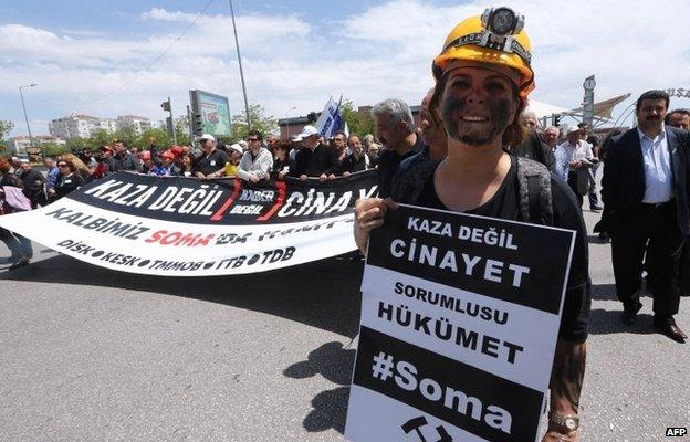 A woman at a protest in Ankara dressed as a miner holds a sign reading: "This is not an accident, this a murder. The government is responsible."