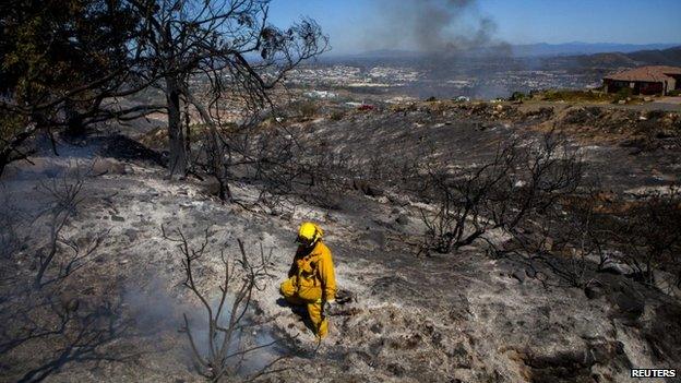 A fire fighter put out embers in San Marcos, California, on 15 May 2014