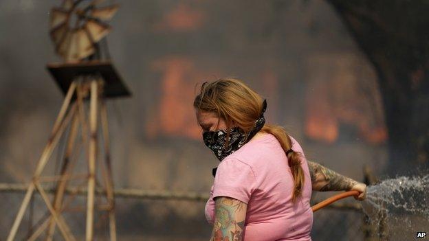 A woman uses water on a fire in Escondido, California, on 15 May 2014