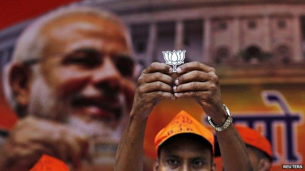 A supporter of Bharatiya Janata Party (BJP) holds a cut-out of lotus