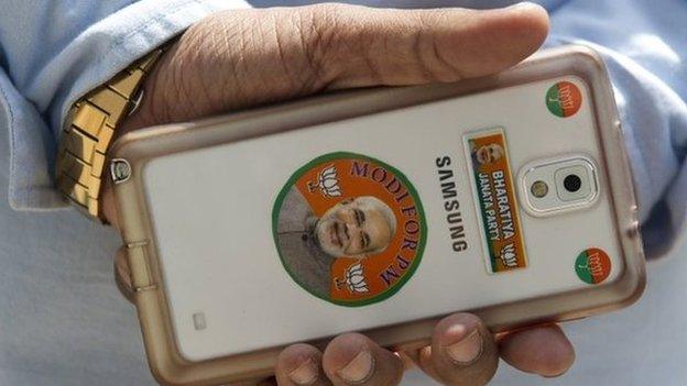 BJP worker holds a smartphone decorated with stickers bearing the image of the Chief Minister of the western Indian state of Gujarat and main opposition Bharatiya Janata Party (BJP) prime ministerial candidate Narendra Modi at the party's head office in New Delhi.