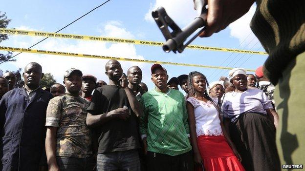 A soldier stands guard in front of a crowd at the scene of the blast in Nairobi (16 May 2014)