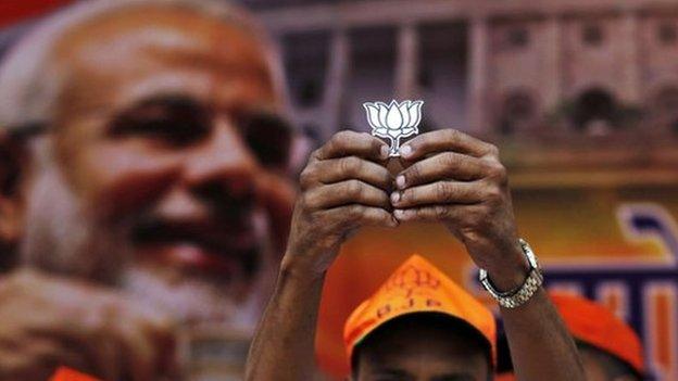 A supporter of Bharatiya Janata Party (BJP) holds a cut-out of lotus