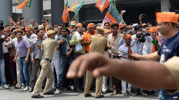 Supporters of unseen Chief Minister of the western Indian state of Gujarat and Bharatiya Janata Party (BJP) prime-ministerial candidate Narendra Modi are held back by security personnel as he arrives at Indira Gandhi International Airport in New Delhi on 17 May 2014