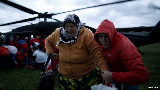 A woman and her son move away from an European Union Force (EUFOR) helicopter after being rescued from the flooded Serici village near Zepce in Bosnia on 17 May 2014