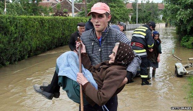 A Serbian rescuer carries an elderly woman in the village of Obrez, south of Belgrade, on 17 May 2014.