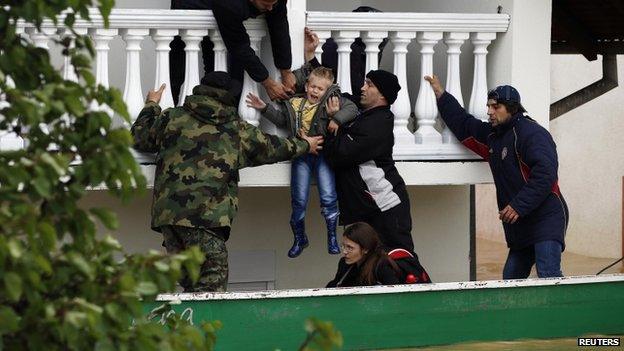 Serbian army soldiers moves a boy from a flooded house in the town of Obrenovac on 17 May 2014