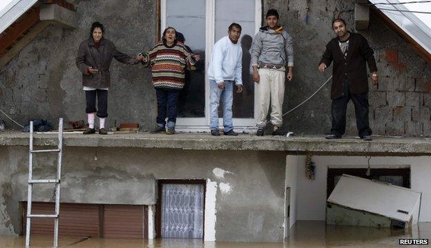 People stand on a terrace of their flooded house as the wait to be evacuated in the town of Obrenovac, southwest of Belgrade, on 16 May 2014