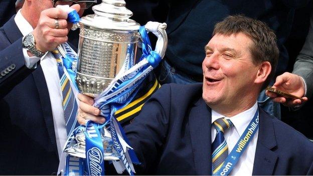 St Johnstone manager Tommy Wright hold the trophy on the open-top bus as it parades through the city