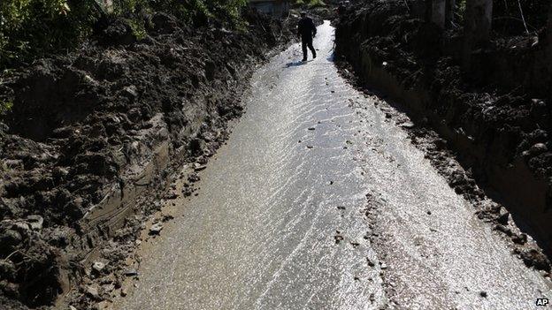 A Bosnian man walks on a broken road after a landslide which swept away eight houses near Kalesija, Bosnia, 150km (93 miles) north of Sarajevo