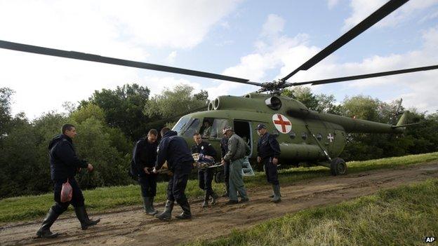 Serbian police officers carry an old woman from a military helicopter during evacuation from Obrenovac, some 30km (18 miles) south-west of Belgrade