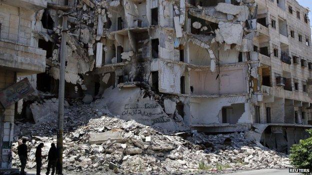 People stand along a damaged street in Bustan al-Basha district in Aleppo (May 2014)