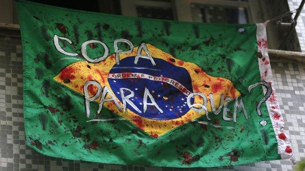 A defaced Brazilian national flag hangs from a window of a house with a slogan that read in Portuguese, "A cup for whom?" in Rio de Janeiro on 20 May, 201