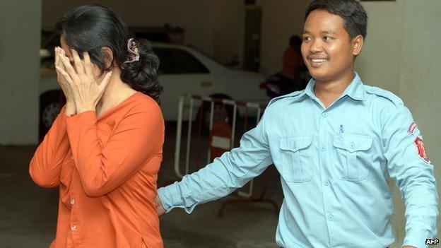 Taiwanese woman Lin Yu Shin (L) covers her face as she is escorted by a Cambodian prison guard (R) at the Phnom Penh Municipal court on 29 April, 2014