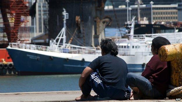 Two of the 75 Indonesian fishermen living on seven rusted Taiwanese-registered fishing boats sit at Cape Town Harbour on 28 November, 2013