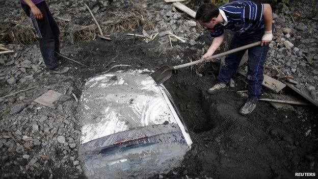 People dig out a car buried after floods and landslides in Topcic Polje