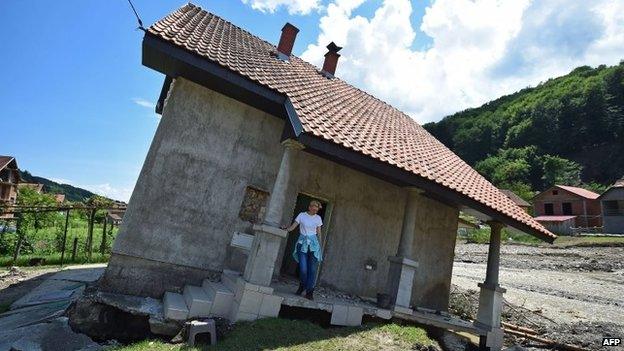 Flood victim Pavlovic Oksana stands on the front porch of her house, damaged by flooding and landslide, in Krupanj