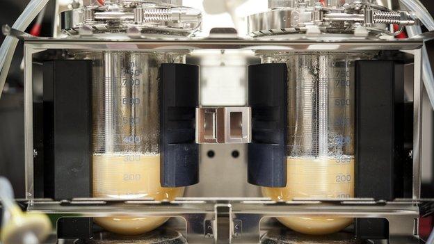 A machine with two vials of milky liquid